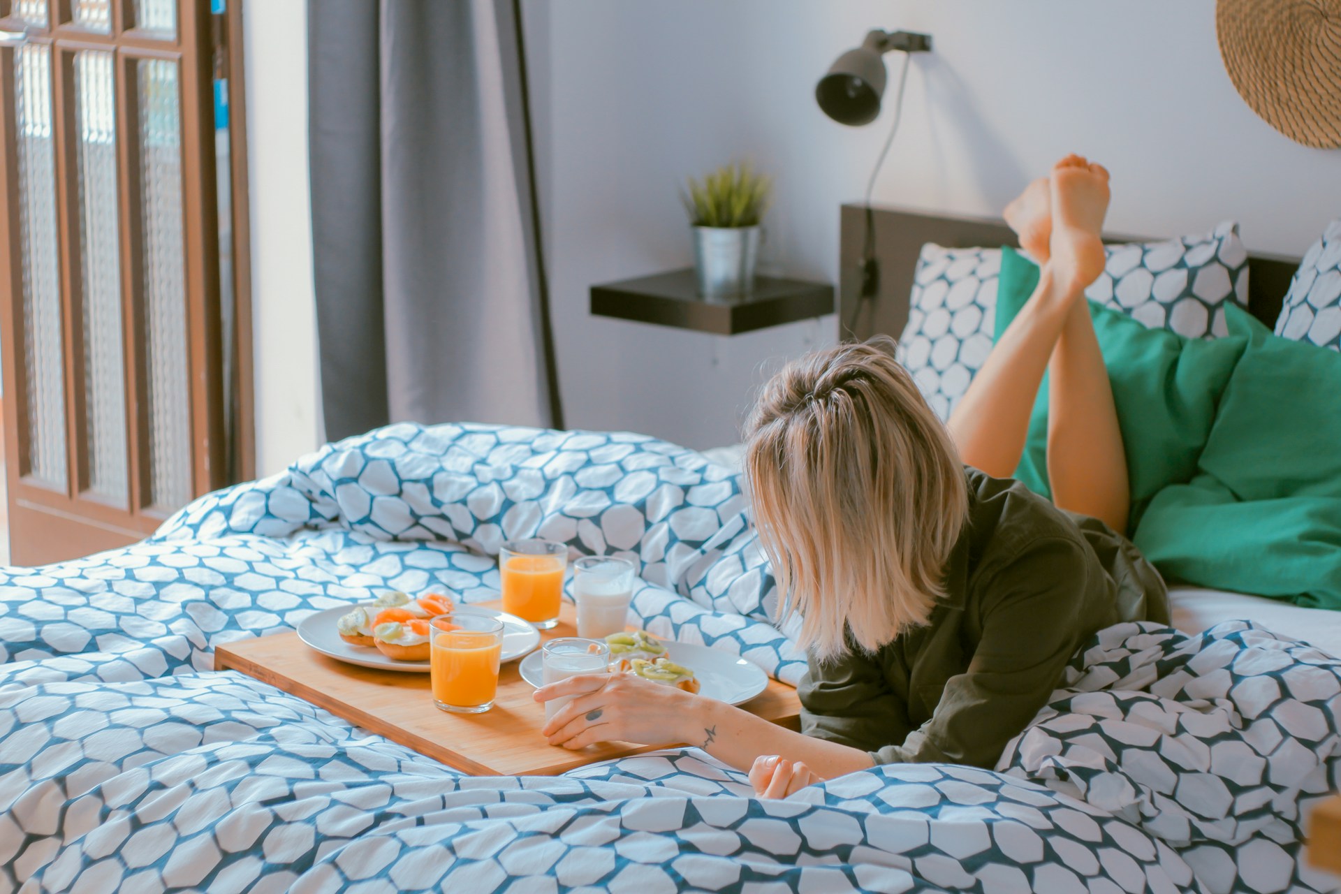 woman-lying-on-bed-having-delicious-breakfast